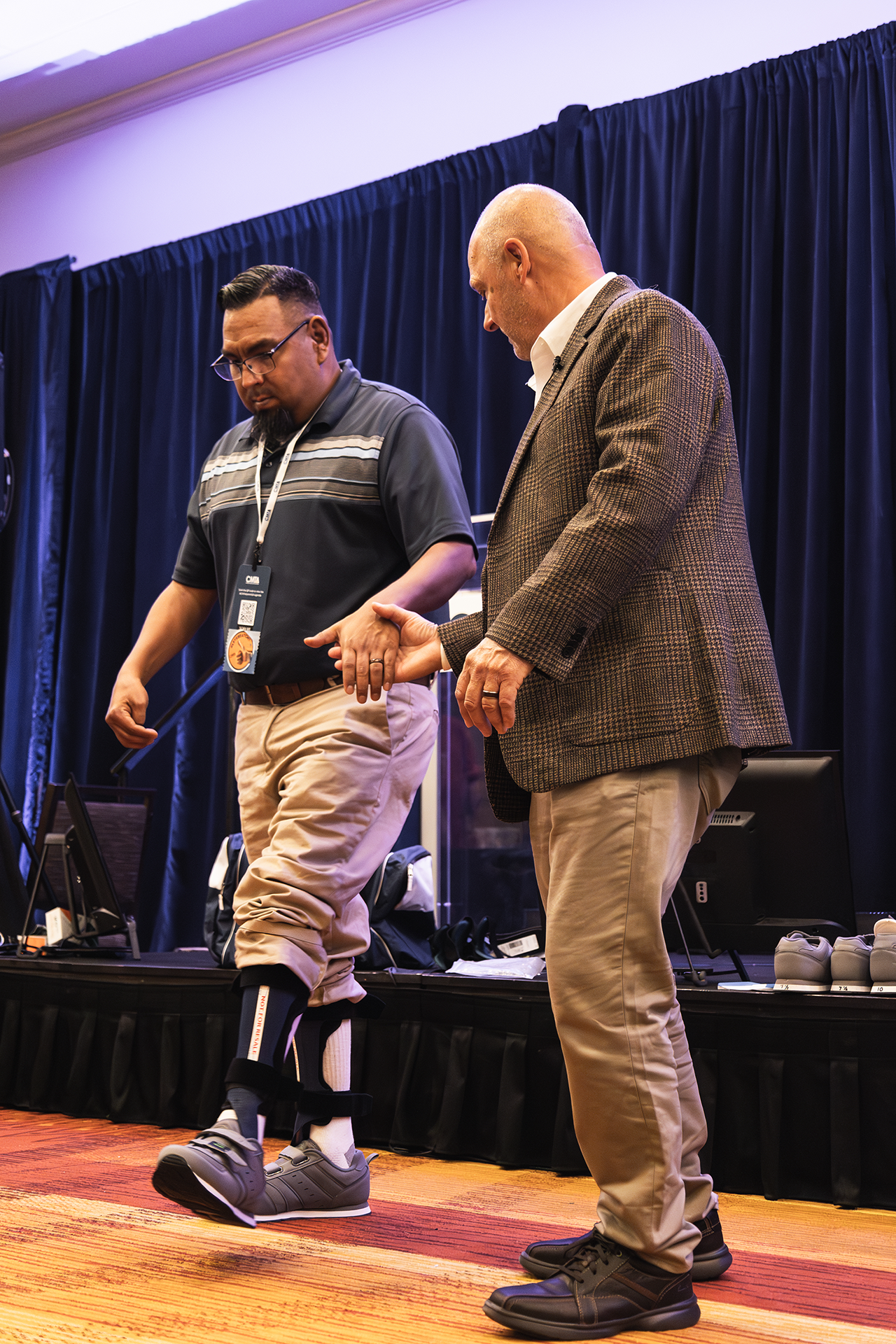 Ken Cornell holding man's hand as he walks in two foot braces