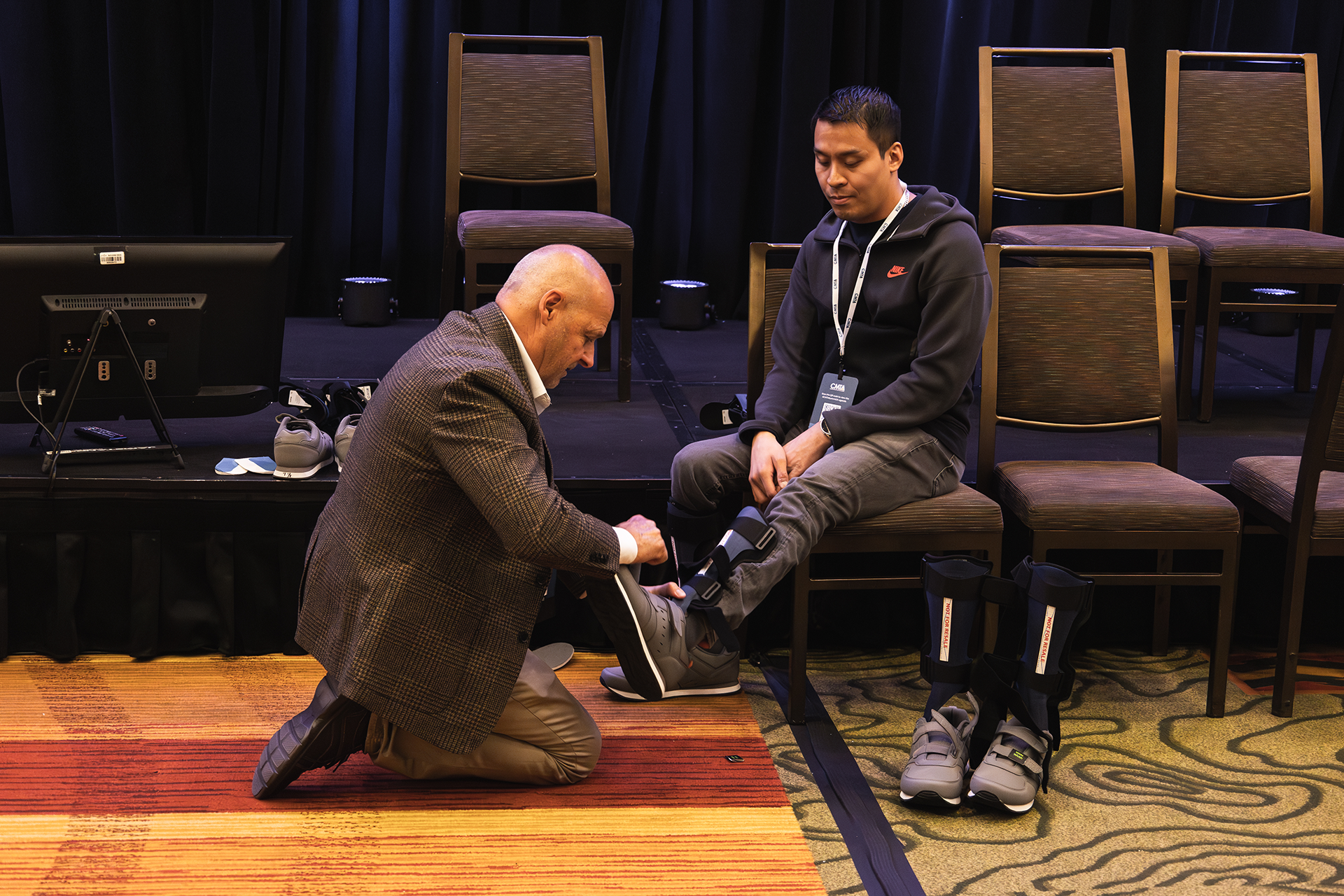 Ken Cornell putting foot brace on seated man